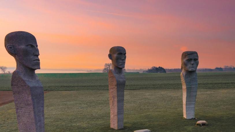 Person looking at stone sculptures Dodekalitten during sunset on Lolland-Falster, Denmark