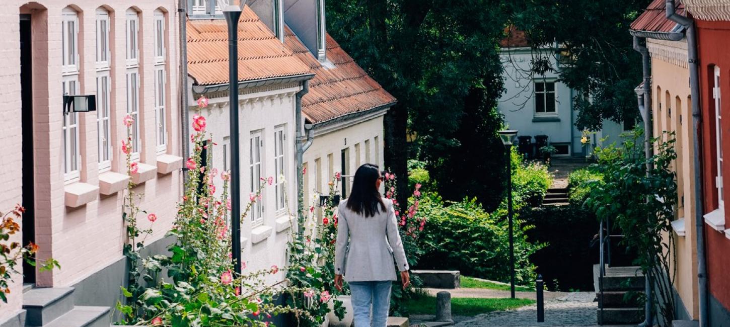 kvinne som går nedover brosteinsgate i Odense 