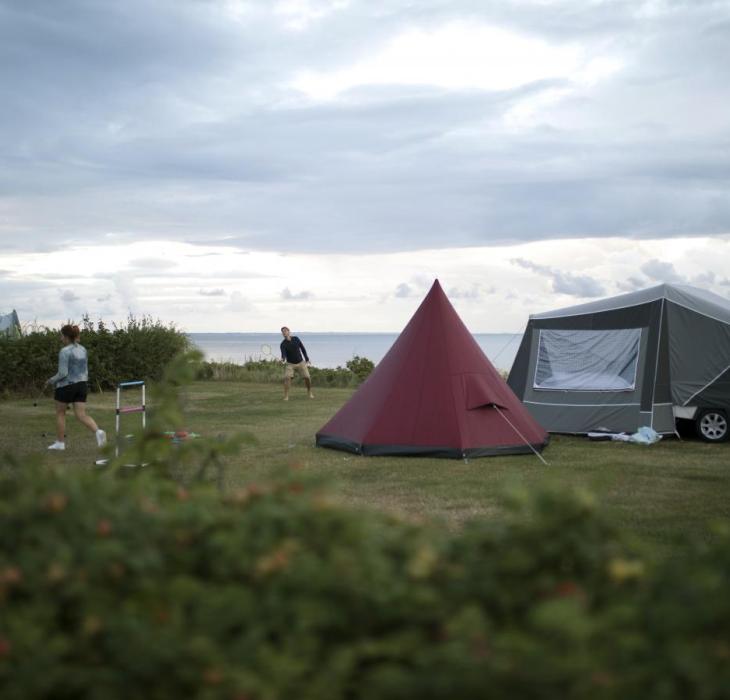 Familie spielt vor einem Camping-Zelt am Strand in Dänemark
